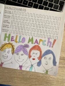 monthly bujo spread for march with healthy goal tracker and doodle ladies heads at the bottom